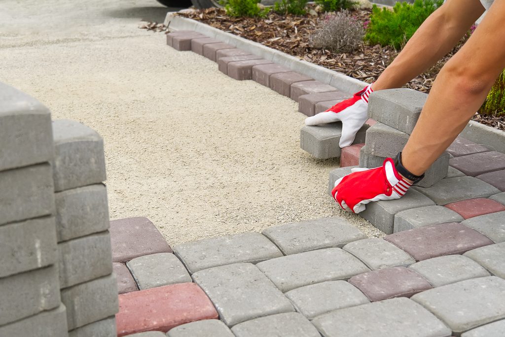 worker laying paving stones. stone pavement, construction worker laying cobblestone rocks on sand